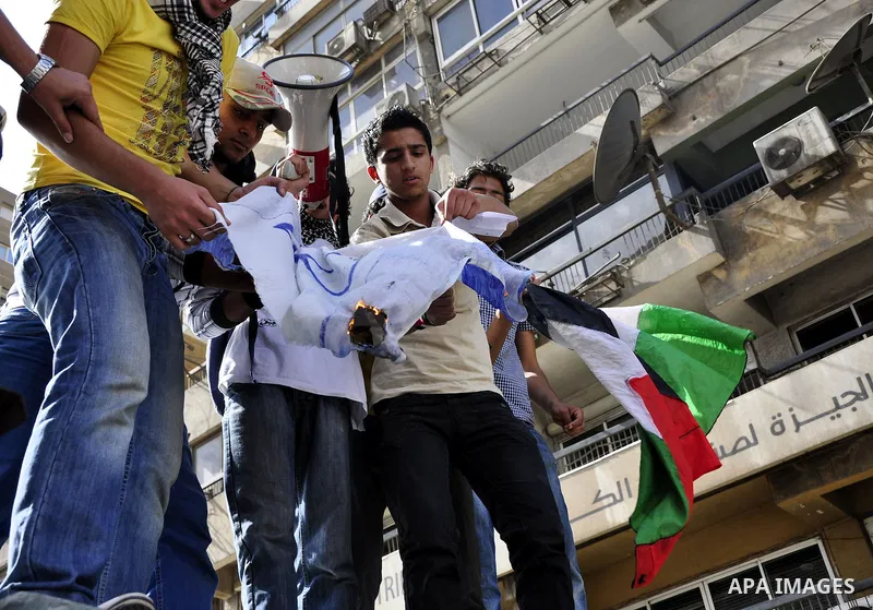 Egyptian protesters burn the Israeli flag and wave the Palestinian flag during a demonstration in front of the Israeli embassy in Cairo on April 29, 2011, calling for opening the border with the Gaza Strip and in support...