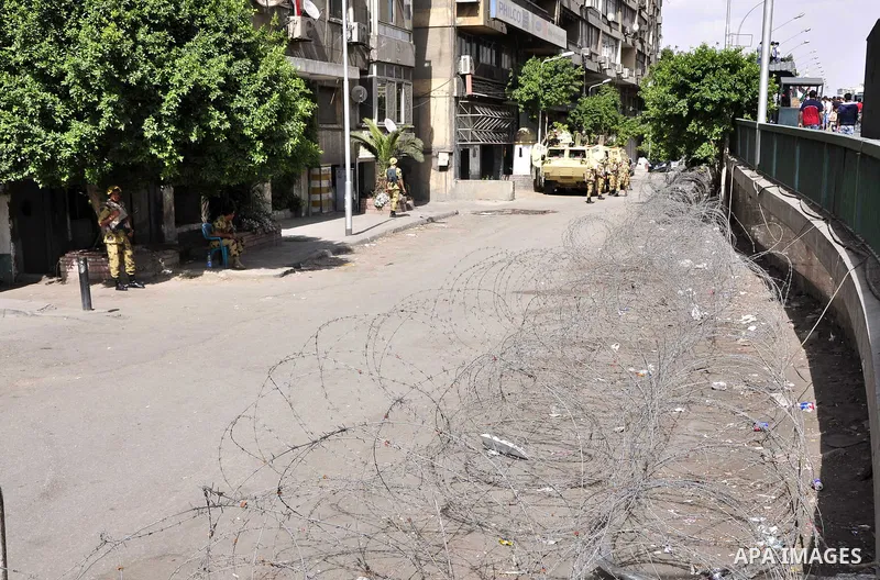 Egyptian army stands guard outside the Israeli embassy as protesters wave the Palestinian flag during a demonstration in front of the Israeli embassy in Cairo on April 29, 2011, calling for opening the border with the Ga...