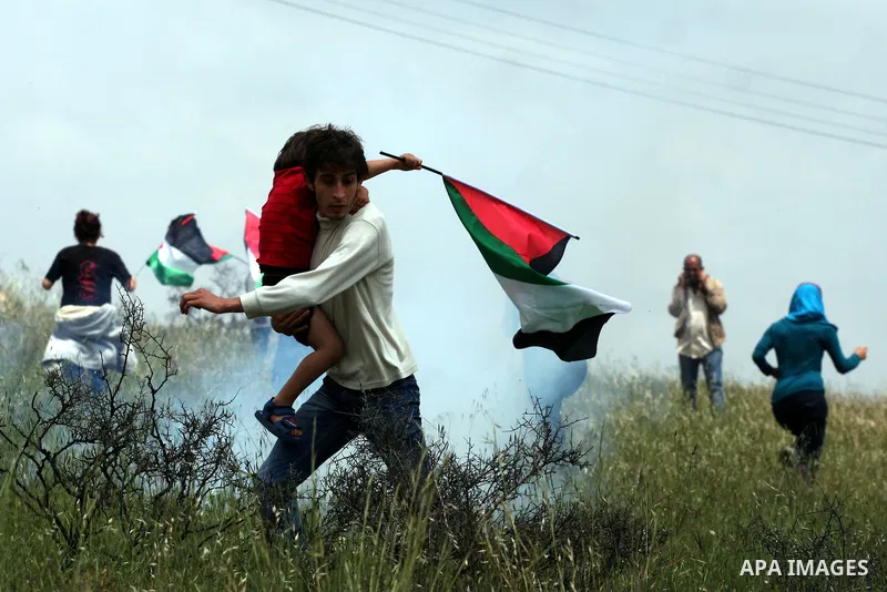 Demonstrators run for cover from tear gas fired by Israeli soldiers during protest against the expropriation of Palestinian land to expand the Jewish settlement of Halmish on April 29, 2011 in the West Bank village of Na...