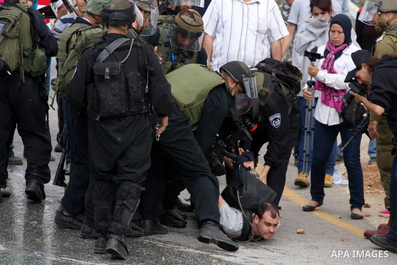 Israeli soldiers detain a pro-Palestinian activist during protest against the expropriation of Palestinian land to expand the Jewish settlement of Halmish on April 29, 2011 in the West Bank village of Nabi Saleh. Photo b...