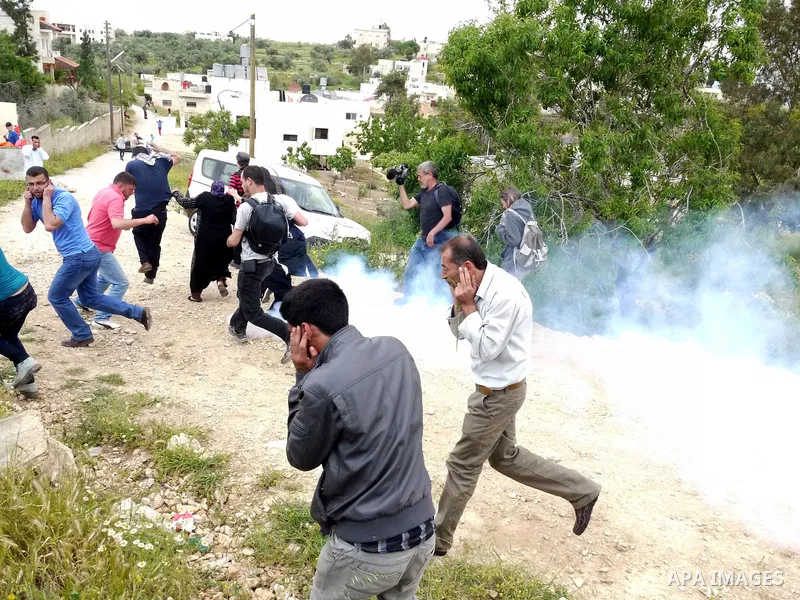 Demonstrators run for cover from tear gas fired by Israeli soldiers during protest against the expropriation of Palestinian land to expand the Jewish settlement of Halmish on April 29, 2011 in the West Bank village of Na...