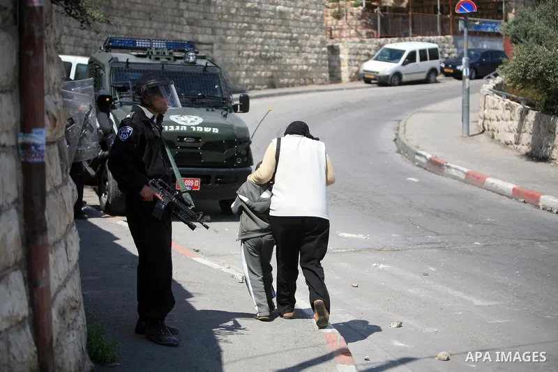 Palestinian woman and her son walk past an Israeli soldier standing guard during clashes in the flashpoint east Jerusalem neighbourhood of Silwan on April 29, 2011.. Photo by Sliman Khader