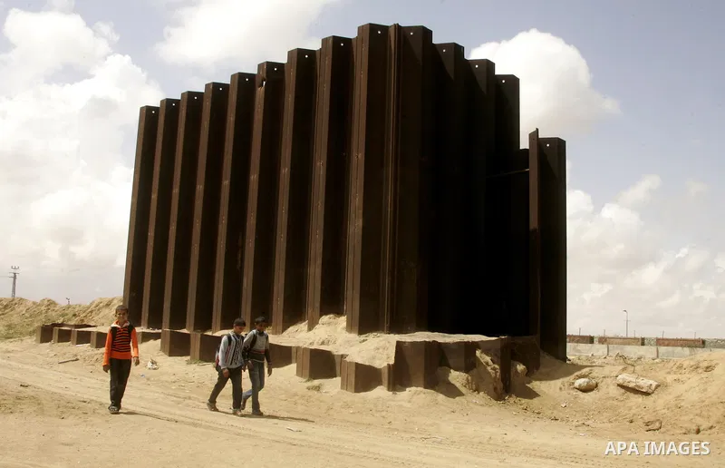 Palestinian boys walk past a segment of what used to be a border fence between Egypt and the Gaza Strip near Rafah on April 30, 2011, a day after Egypt said it will permanently open the Rafah border crossing as part of i...