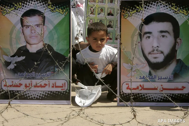A child sits next to images of Palestinian prisoners being held in Israeli jails during a rally on May 01, 2011, calling for their release in Rafah town in the southern Gaza Strip. Photo by Abed Rahim Khatib