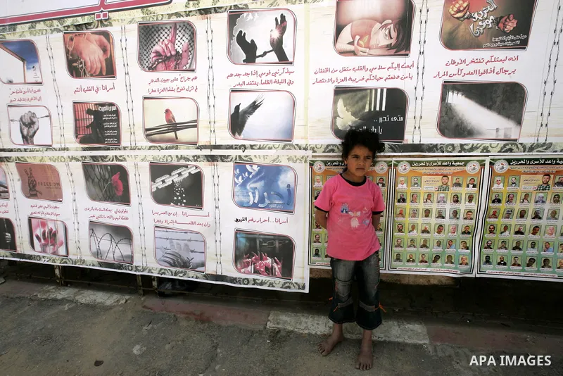 A child sits next to images of Palestinian prisoners being held in Israeli jails during a rally on May 01, 2011, calling for their release in Rafah town in the southern Gaza Strip. Photo by Abed Rahim Khatib