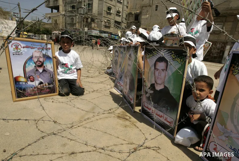 Children sit next to images of Palestinian prisoners being held in Israeli jails during a rally on May 01, 2011, calling for their release in Rafah town in the southern Gaza Strip. Photo by Abed Rahim Khatib