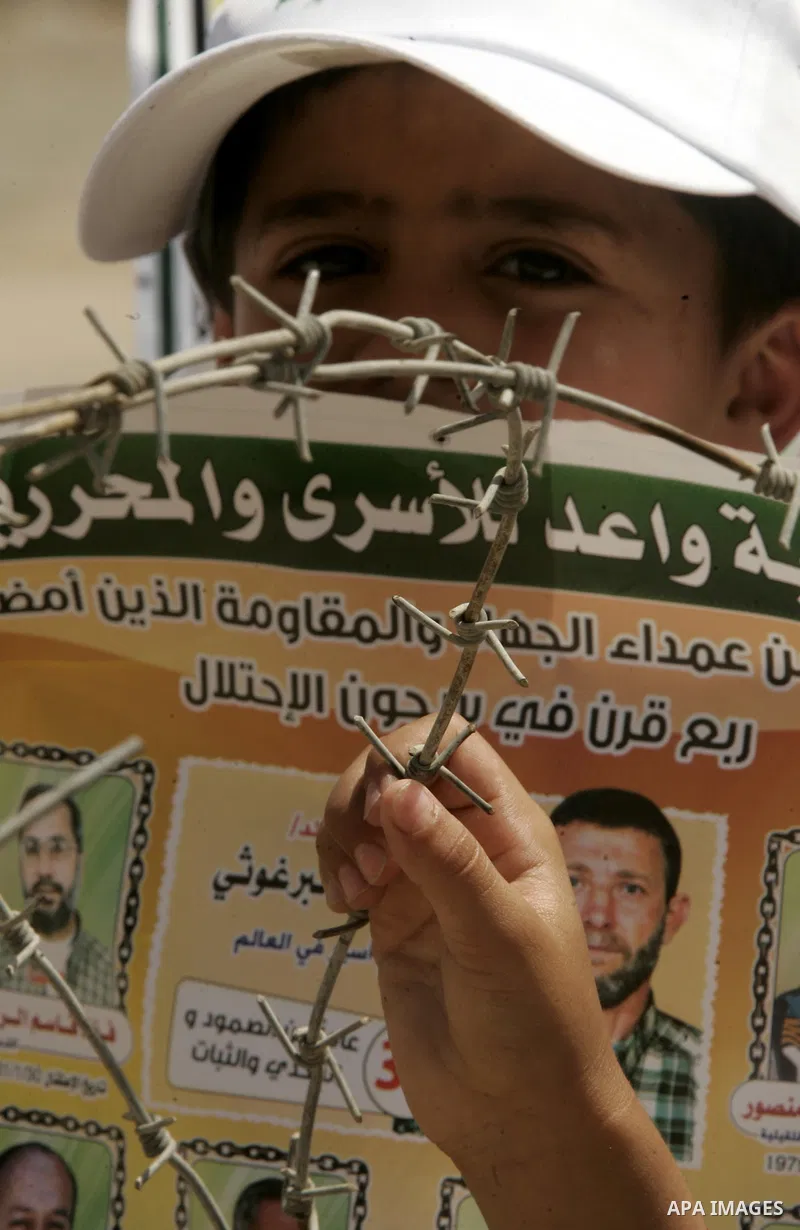 A child holds up images of Palestinian prisoners being held in Israeli jails during a rally on May 01, 2011, calling for their release in Rafah town in the southern Gaza Strip. Photo by Abed Rahim Khatib