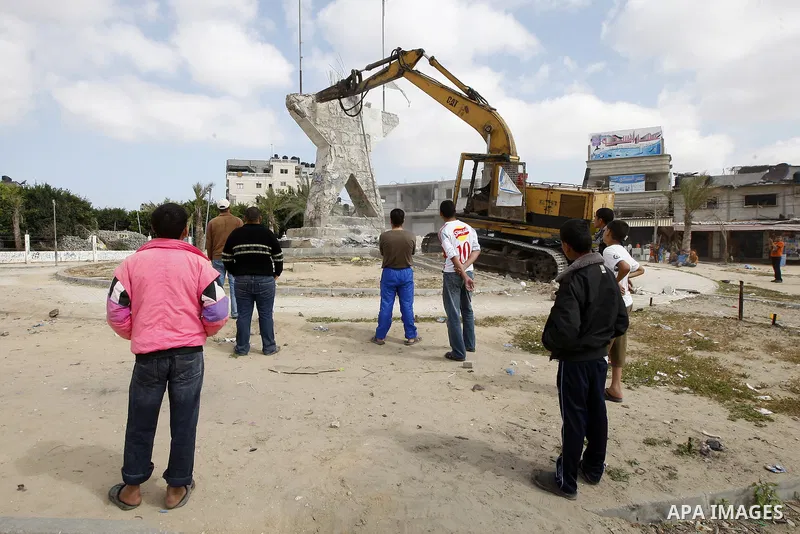 Palestinians look at a bulldozer demolishing a star figure as volunteers from the ruling Islamic Hamas movement took to the street in a project entitled "Gaza is the most beautiful despite the blockade" to mark workers'...