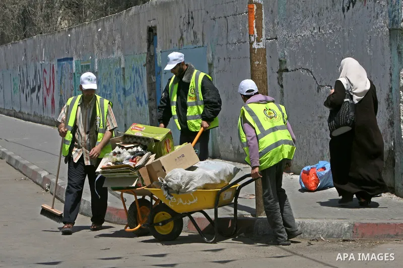 Members of the ruling Islamic Hamas movement sweep the street as volunteers took to the street in a project entitled "Gaza is the most beautiful despite the blockade" to mark workers' May Day in Rafah town In Gaza Strip,...