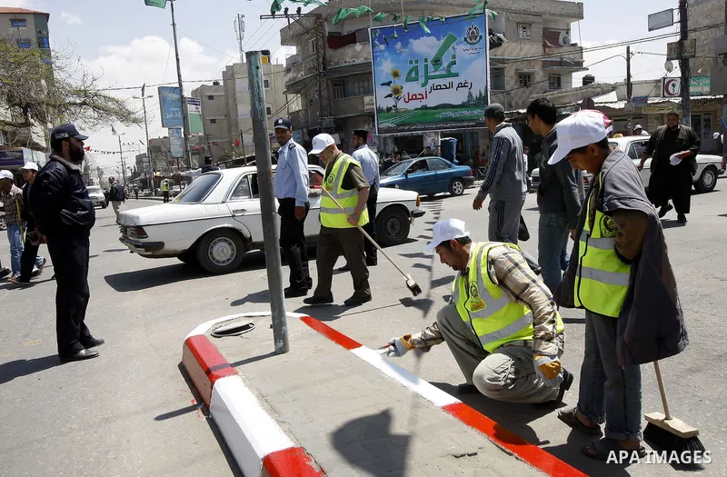 Members of the ruling Islamic Hamas movement paint the side walks as volunteers took to the street in a project entitled "Gaza is the most beautiful despite the blockade" to mark workers' May Day in Rafah town In Gaza St...