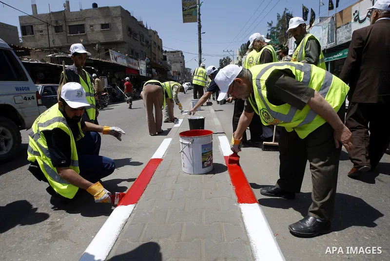 Members of the ruling Islamic Hamas movement paint the side walks as volunteers took to the street in a project entitled "Gaza is the most beautiful despite the blockade" to mark workers' May Day in Rafah town In Gaza St...