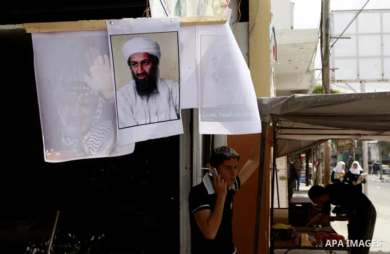 Palestinians walk past a poster of Osama bin Laden, in the southern Gaza Strip town of Rafah on May 2, 2011. The United States has killed Al-Qaeda leader Osama bin Laden nearly 10 years after the September 11, 2001 attac...