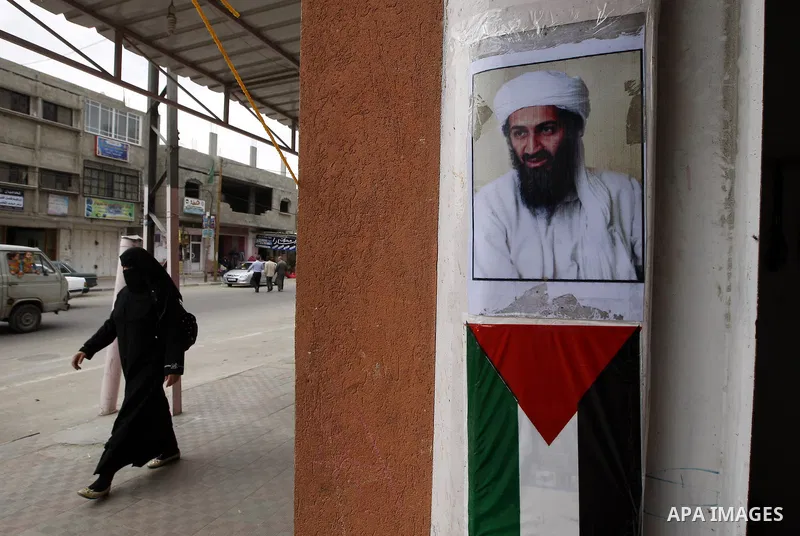 Palestinians walk past a poster of Osama bin Laden, in the southern Gaza Strip town of Rafah on May 2, 2011. The United States has killed Al-Qaeda leader Osama bin Laden nearly 10 years after the September 11, 2001 attac...