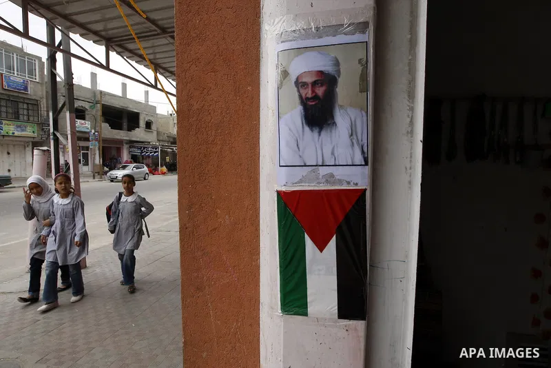 Palestinians walk past a poster of Osama bin Laden, in the southern Gaza Strip town of Rafah on May 2, 2011. The United States has killed Al-Qaeda leader Osama bin Laden nearly 10 years after the September 11, 2001 attac...