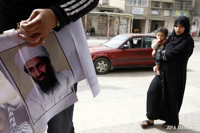 Palestinians walk past a poster of Osama bin Laden, in the southern Gaza Strip town of Rafah on May 2, 2011. The United States has killed Al-Qaeda leader Osama bin Laden nearly 10 years after the September 11, 2001 attac...