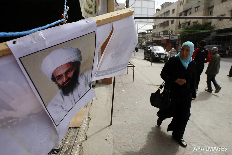 Palestinians walk past a poster of Osama bin Laden, in the southern Gaza Strip town of Rafah on May 2, 2011. The United States has killed Al-Qaeda leader Osama bin Laden nearly 10 years after the September 11, 2001 attac...
