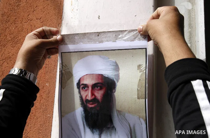 Palestinians walk past a poster of Osama bin Laden, in the southern Gaza Strip town of Rafah on May 2, 2011. The United States has killed Al-Qaeda leader Osama bin Laden nearly 10 years after the September 11, 2001 attac...