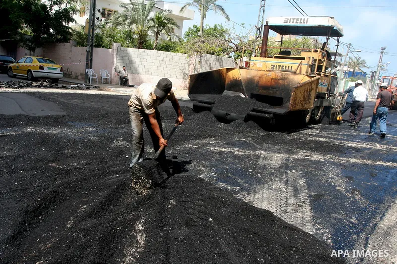 Palestinian workers lay asphalt as a street is paved in Gaza City, on May 3, 2011. Photo by Mohammed Asad