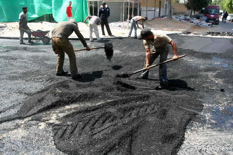 Palestinian workers lay asphalt as a street is paved in Gaza City, on May 3, 2011. Photo by Mohammed Asad