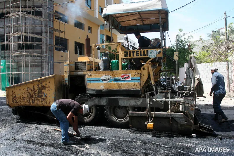 Palestinian workers lay asphalt as a street is paved in Gaza City, on May 3, 2011. Photo by Mohammed Asad