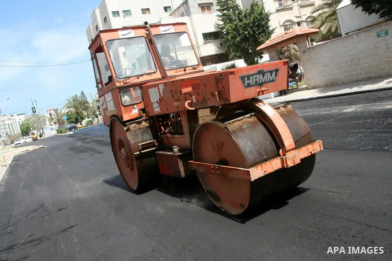 Palestinian workers lay asphalt as a street is paved in Gaza City, on May 3, 2011. Photo by Mohammed Asad