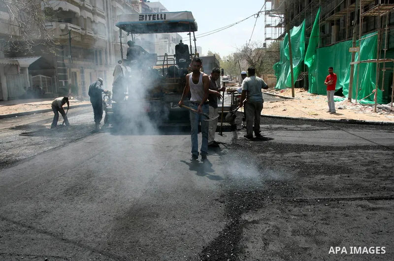 Palestinian workers lay asphalt as a street is paved in Gaza City, on May 3, 2011. Photo by Mohammed Asad