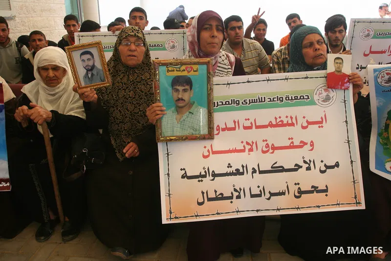 Palestinian women holds a photograph of her relative held in an Israeli jail as she takes part in a hunger strike together with others to show solidarity with their jailed relatives at the headquarters of the Internation...