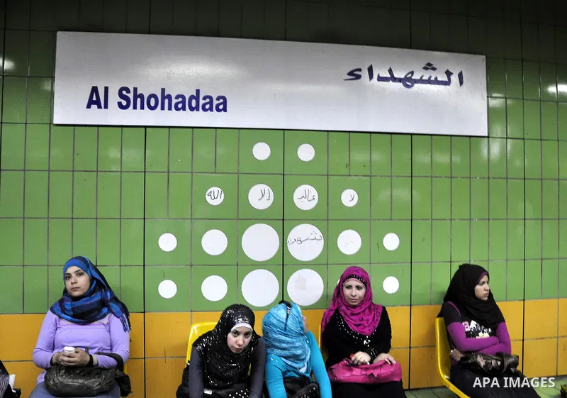 Egyptian women wait at a metro station under a placard holding the name Al Shohadaa "the Martyrs" in Arabic and English in Cairo, Egypt on May 03, 2011. Al Shohadaa is the new name of the metro which called in the past i...