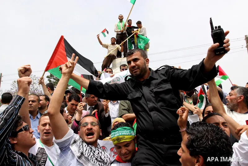 Palestinians wave with national flag and shout slogans during a rally celebrating the signing of a reconciliation deal in Gaza city on May 4,2011. Hundreds of Palestinians have gathered to cheer on a unity agreement bein...