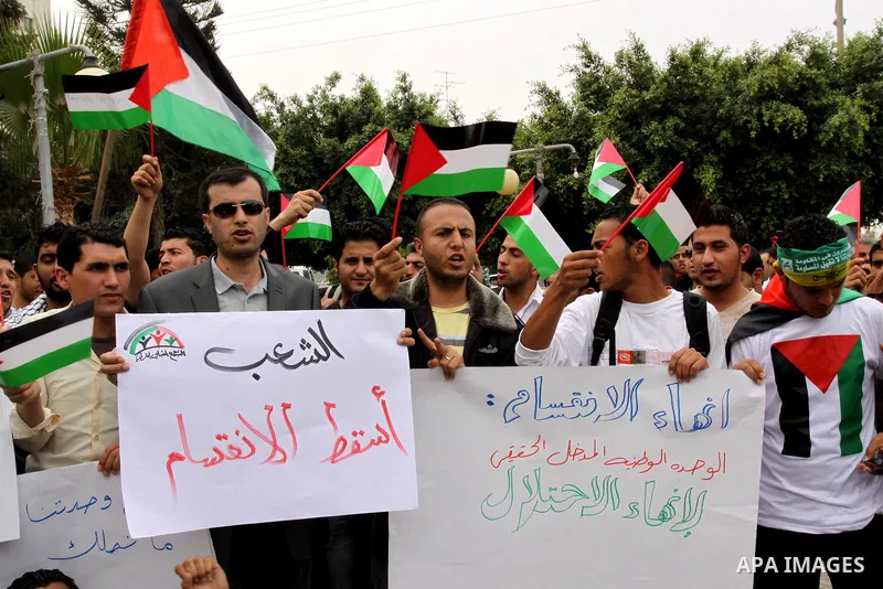 Palestinians wave with national flag and shout slogans during a rally celebrating the signing of a reconciliation deal in Gaza city on May 4,2011. Hundreds of Palestinians have gathered to cheer on a unity agreement bein...