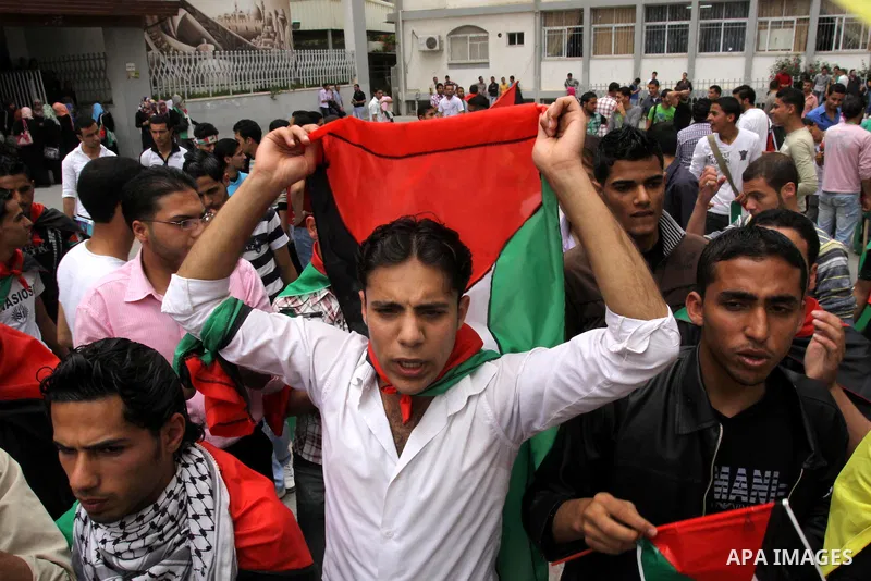 Palestinians wave with national flag and shout slogans during a rally celebrating the signing of a reconciliation deal in Gaza city on May 4,2011. Hundreds of Palestinians have gathered to cheer on a unity agreement bein...
