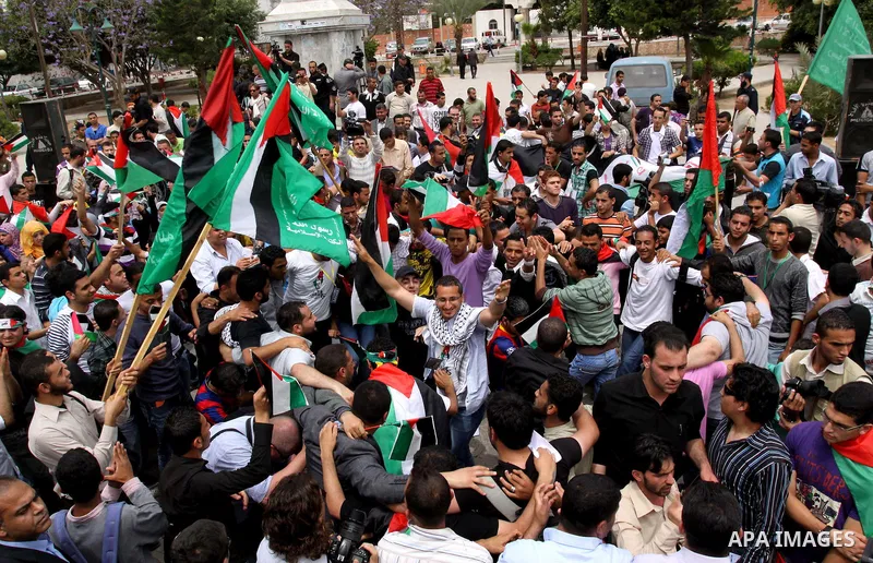 Palestinians wave with national flag and shout slogans during a rally celebrating the signing of a reconciliation deal in Gaza city on May 4,2011. Hundreds of Palestinians have gathered to cheer on a unity agreement bein...