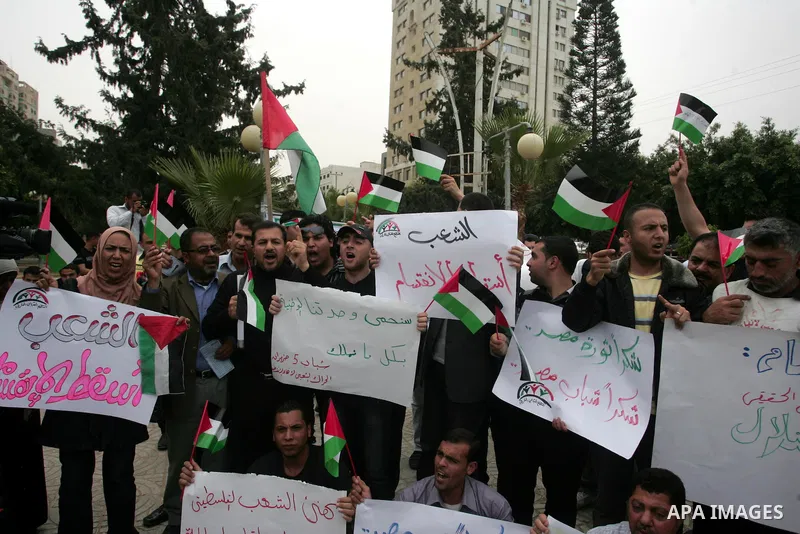 Palestinians wave with national flag and shout slogans during a rally celebrating the signing of a reconciliation deal in Gaza city on May 4,2011. Hundreds of Palestinians have gathered to cheer on a unity agreement bein...