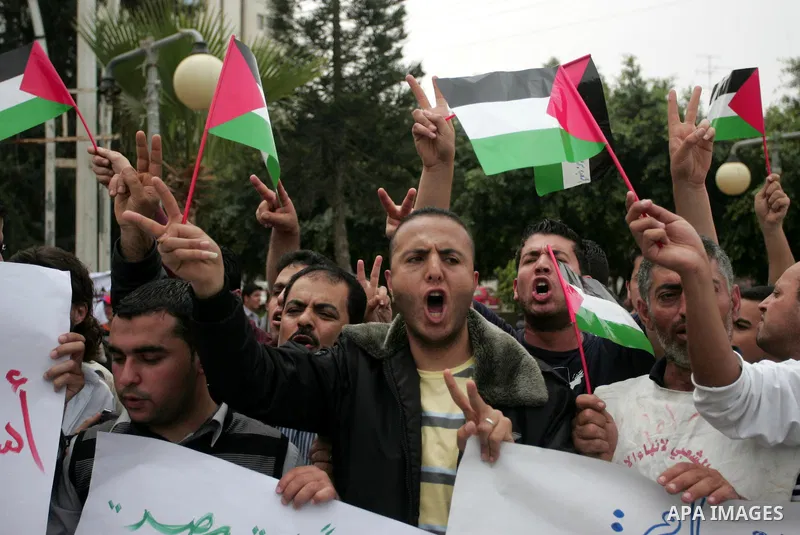 Palestinians wave with national flag and shout slogans during a rally celebrating the signing of a reconciliation deal in Gaza city on May 4,2011. Hundreds of Palestinians have gathered to cheer on a unity agreement bein...