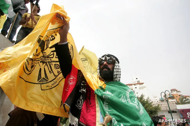 Palestinians wave with Hamas movement and Fatah party flags during a rally celebrating the signing of a reconciliation deal in Gaza city on May 4,2011. Hundreds of Palestinians have gathered to cheer on a unity agreement...