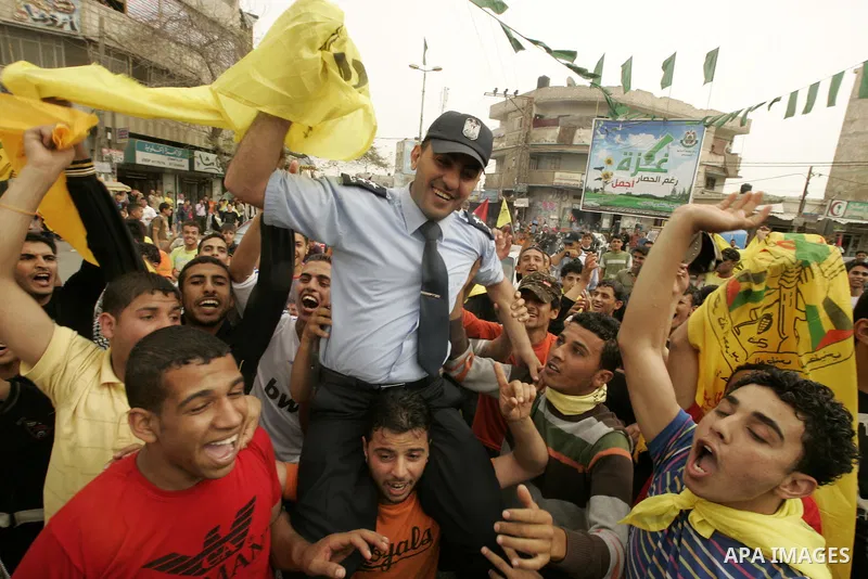 A Palestinian Hamas policeman holds the Fatah flag as he joins celebrations marking the political reconciliation agreement during a rally in Rafah, southern Gaza Strip, on May 4, 2011 as Palestinians in the West Bank and...