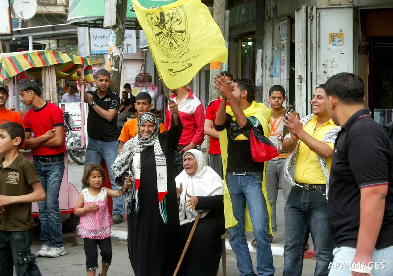 Palestinians wave with Fatah party flags during celebrations marking the political reconciliation agreement during a rally in Rafah, southern Gaza Strip, on May 4, 2011 as Palestinians in the West Bank and Gaza Strip gat...