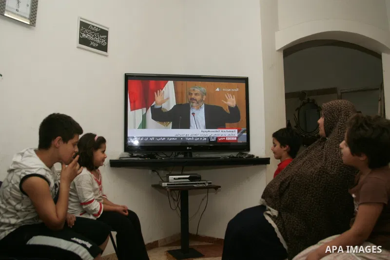Palestinians watch on TV the signing of the political reconciliation agreement between Fatah and Hamas at their home in Jerusalem's old city on May 04, 201, as Palestinians in the West Bank and Gaza Strip gather to celeb...