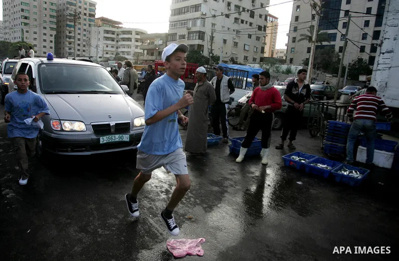 Palestinian schoolboys run past a fish market in Gaza City on May 5, 2011 as they compete in the Gaza Strip's first-ever marathon which runs the entire length of the coastal enclave. Photo by Mohammed Othman