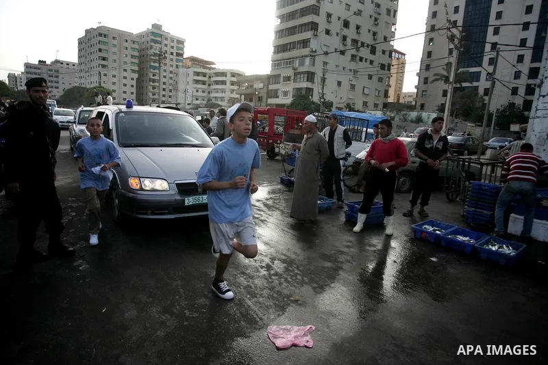 Palestinian schoolboys run past a fish market in Gaza City on May 5, 2011 as they compete in the Gaza Strip's first-ever marathon which runs the entire length of the coastal enclave. Photo by Mohammed Othman