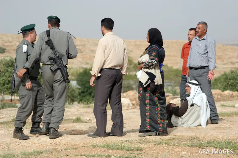 Israeli soldiers stand guard as members of a Palestinian family retrieve items from the rubble of their home after their shacks and tents were destroyed by Israeli bulldozers near the Jewish settlement of Sosia, in the v...