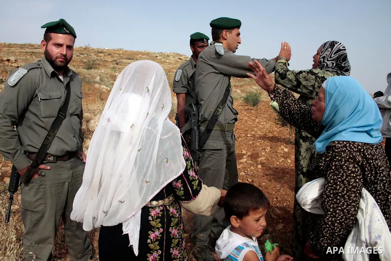 Israeli soldiers stand guard as members of a Palestinian family retrieve items from the rubble of their home after their shacks and tents were destroyed by Israeli bulldozers near the Jewish settlement of Sosia, in the v...