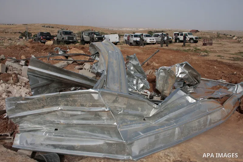 Israeli soldiers stand guard as members of a Palestinian family retrieve items from the rubble of their home after their shacks and tents were destroyed by Israeli bulldozers near the Jewish settlement of Sosia, in the v...