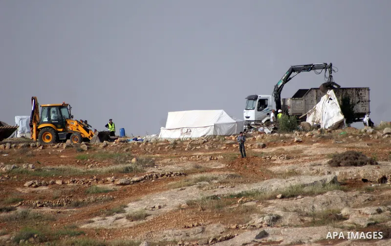 Israeli soldiers stand guard as members of a Palestinian family retrieve items from the rubble of their home after their shacks and tents were destroyed by Israeli bulldozers near the Jewish settlement of Sosia, in the v...