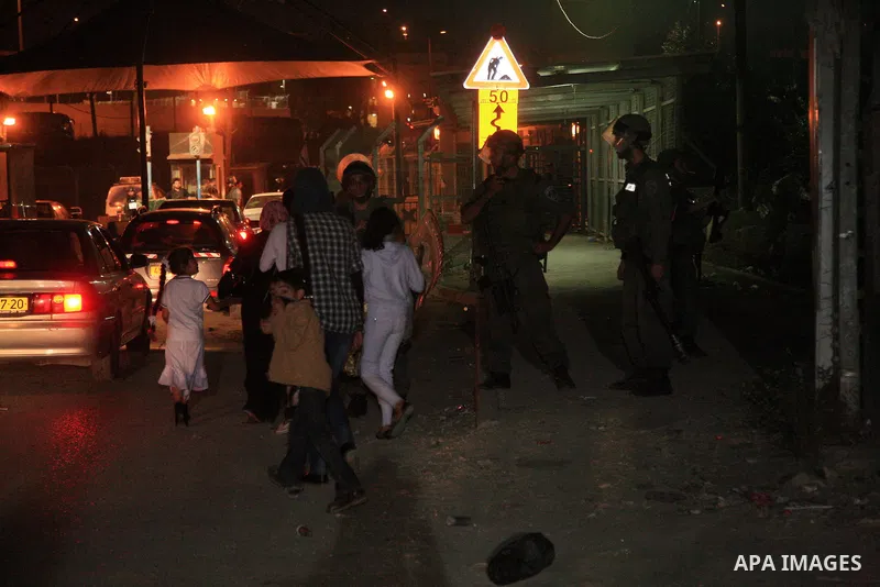Palestinians walk past Israeli soldiers standing guard during clashes with stone-throwers in the flashpoint east Jerusalem's Shu'fat refugee camp on May 5, 2011. Photo by Sliman Khader