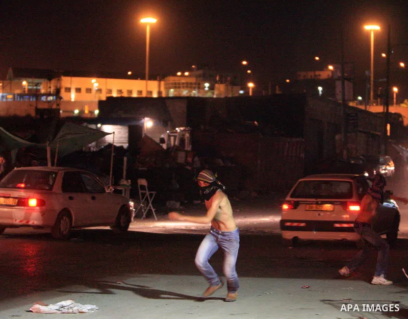 Masked Palestinian youths throw stones during clashes with Israeli police in the flashpoint east Jerusalem's Shu'fat refugee camp on May 5, 2011. Photo by Sliman Khader