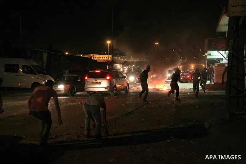 Masked Palestinian youths throw stones during clashes with Israeli police in the flashpoint east Jerusalem's Shu'fat refugee camp on May 5, 2011. Photo by Sliman Khader