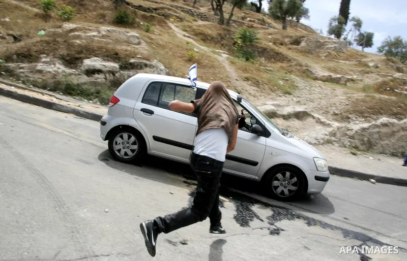 A masked Palestinian youth hurls stones toward a jewish settler car during clashes in the flashpoint east Jerusalem neighbourhood of Silwan on May 6,2011. Photo by Mahfouz Abu Turk