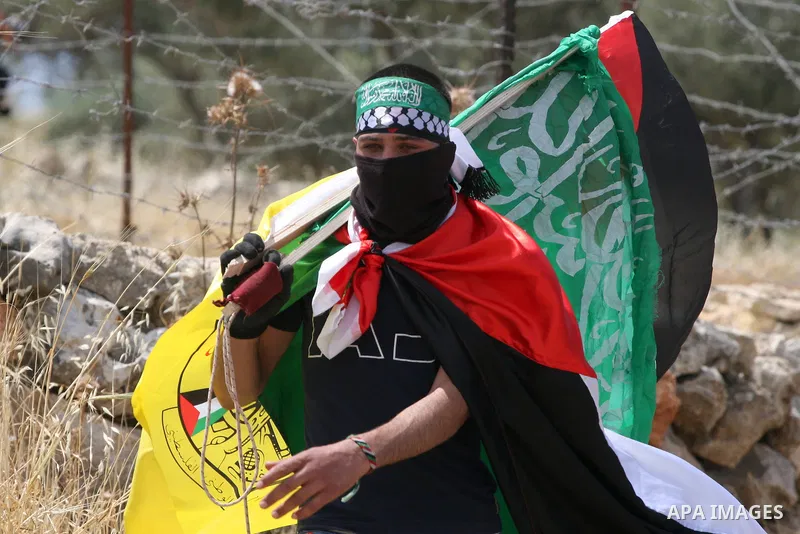 A Palestinian protestor carries the Hamas and Fatah flags during a rally on May 6, 2011, in the Israeli-occupied West Bank village of Bilin, to celebrate the political unity reconciliation deal between the Hamas Islamist...