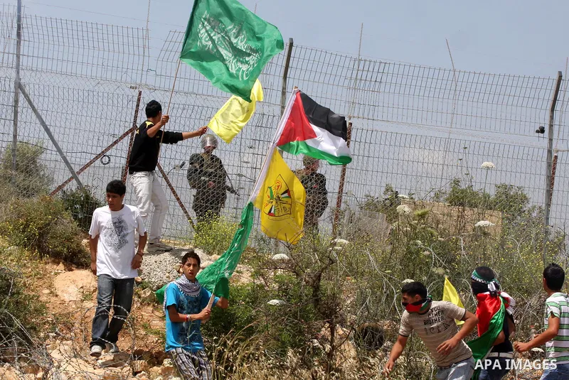 Palestinian protestors carry the Hamas and Fatah flags during a rally on May 6, 2011, in the Israeli-occupied West Bank village of Bilin, to celebrate the political unity reconciliation deal between the Hamas Islamist mo...